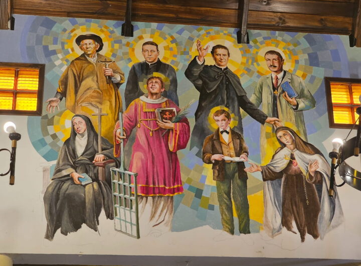 Mural de arte sacro realizado por Hugo Lazzarini que representa a santos y figuras emblemáticas de la Iglesia Católica, incluyendo al Cura Brochero, San Juan Bosco, San Lorenzo con su parrilla, Artémides Zatti, Ceferino Namuncurá, Santo Domingo Savio y Mama Antula. La obra destaca por sus características aureolas geométricas de colores vibrantes y un estilo de iconografía moderna.